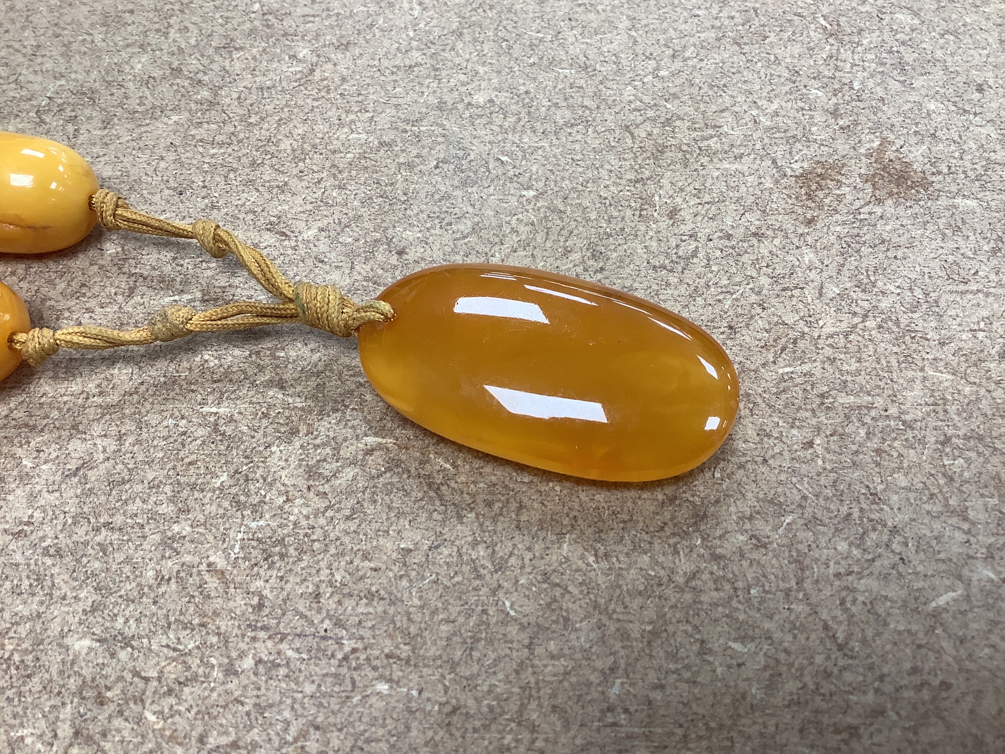 A single strand oval amber bead pendant necklace, 92cm, gross weight 60 grams.